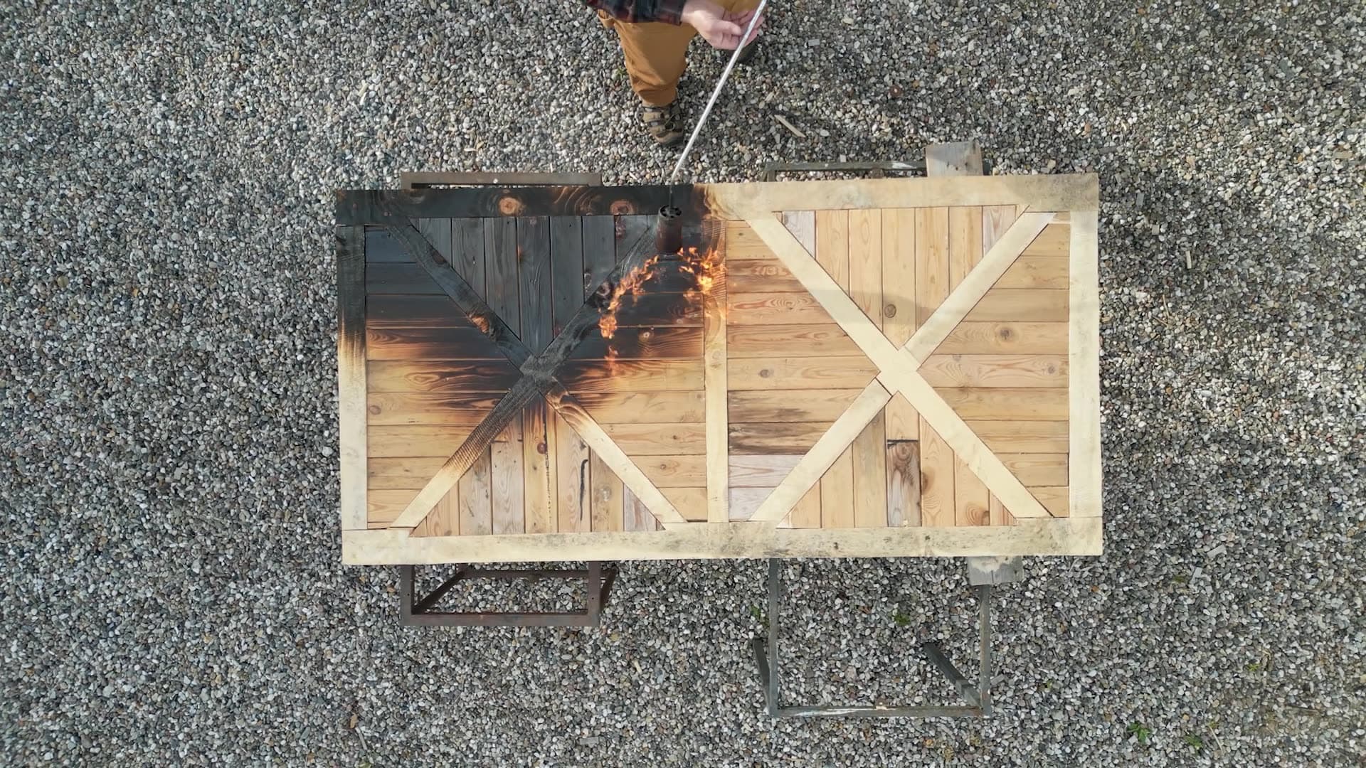 Burning the timber frame door with a weed burner, half charred, half raw wood